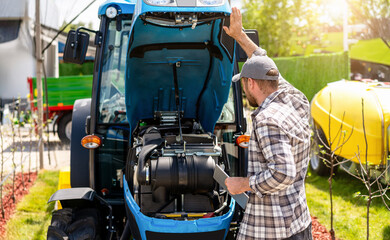 Male technician diagnosing tractor engine at farm