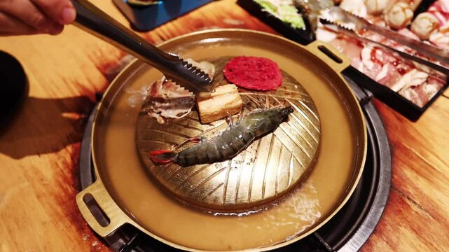 Top view of the traditional asian grill or hot pot in Thail restaurant cooking seafood and meat