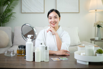 Beautiful woman in bathrobe sitting at home with skincare products, ready for a beauty routine.
