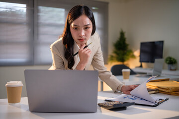 Focused female executive analyzing corporate data reports and making business decisions.