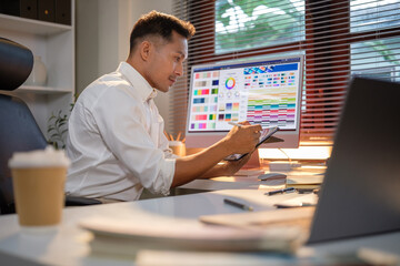 Creative professional using tablet and stylus while working on design project in modern office.
