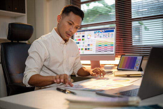 Creative male graphic designer reviewing design elements while working on a digital color scheme project.