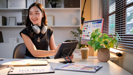 Happy female graphic designer reviewing color swatches while working on a creative project.