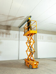 Construction worker using scissor lift to install ceiling beams in warehouse