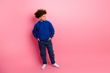 Charming young boy in a blue hoodie posing confidently against a bright pink background with a cheerful expression