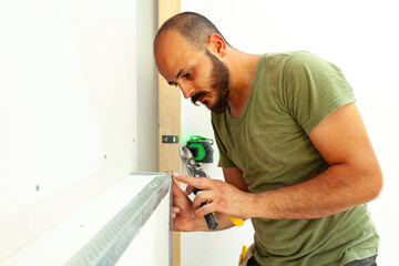 Construction Worker Installing Metal Corner Bead on Drywall Using Snips