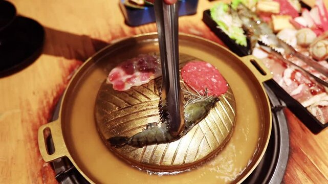 Top view of the traditional asian grill or hot pot in Thail restaurant cooking seafood and meat