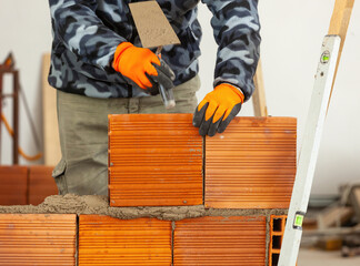 Construction worker building a wall using hollow bricks and cement