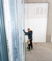 Construction worker installing aluminum studs for drywalling a new wall