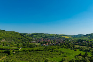 Expansive view of a picturesque village surrounded by lush greenery and rolling hills under a...
