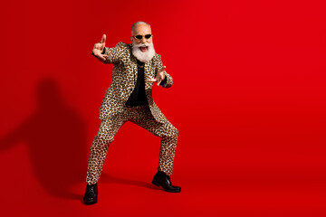 Charismatic elderly man in a leopard print suit striking a playful pose on a vibrant red background