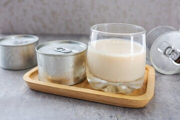 Glass of  fresh milk with canned milk, tinned milk on grey background	