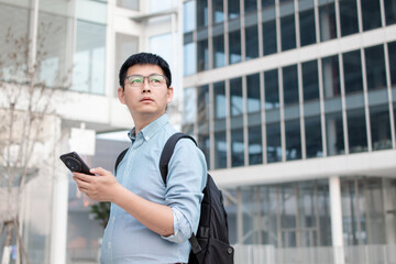 Fototapeta premium asian businessman using smart phone out of office building