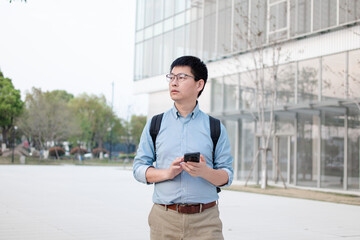 asian businessman using smart phone out of office building