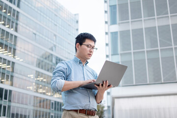Fototapeta premium asain businessman working on laptop outside of office building