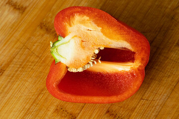 Half of a red bell pepper on a wooden cutting board.