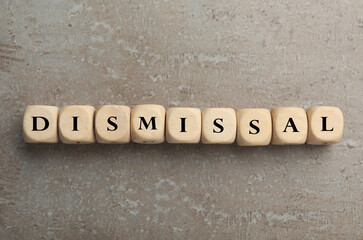 Word Dismissal made of wooden cubes on grey textured background, top view