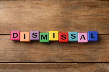 Word Dismissal made of colorful cubes on wooden background, top view