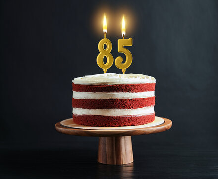 Yummy cake with burning number shaped candles on black background. 85th birthday or other special occasion