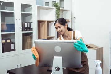 Young housekeeper wearing gloves and cleaning the table with a rag and cleaning spray. Professional...