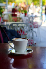 Cappuccino cup against bokeh outdoor coffee house background