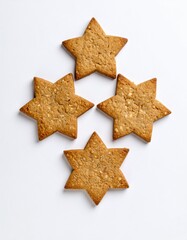 Obraz premium Cuatro galletas de avena casera con forma de estrella dispuestas en cruz sobre fondo blanco, textura visible y color dorado suave.