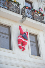 toy Santa Claus climbs the stairs to the balcony of a concrete building