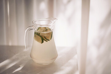 Refreshing pitcher of homemade lemonade infused with fresh lime slices and mint leaves captured in soft afternoon light