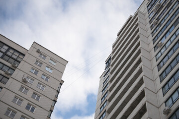 Modern residential buildings reaching towards the sky, showcasing architectural design and urban living with a backdrop of cloudy blue sky