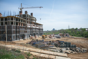 construction site with a warehouse of building materials and a tower crane, which is used to build a new large multi-storey brick apartment building