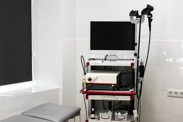 A modern endoscopy system with a large monitor, processing unit, and endoscopes is on a mobile cart...