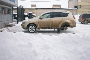 dirty car without a rear wheel changes old tires for new ones in winter