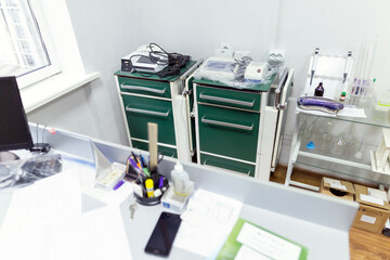 Two medical carts with green drawers hold laboratory equipment, test tube racks, and various medical supplies in a clean clinic room