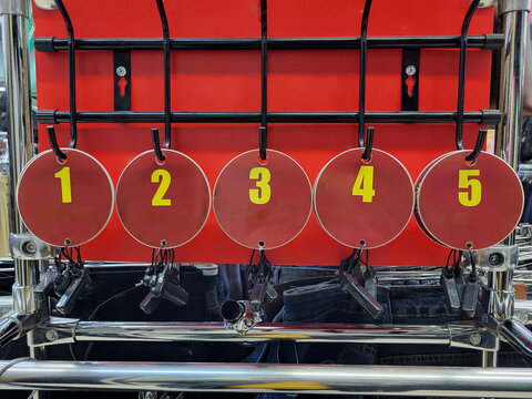 Round red tags with numbers hang on the hooks of a hanger in a clothing store. - Powered by Adobe