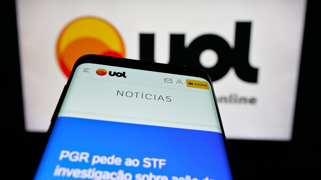 Stuttgart, Germany - 05-27-2025: Mobile phone with website of Brazilian web platform Universo Online (UOL) on screen in front of logo. Focus on top-left of phone display.