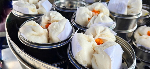 Stuffed steamed buns arranged in Stainless steel steamer for heating and selling. Steamed buns with minced pork filling, salted egg pork filling, Dough shaped into balls, filled with pig various.
