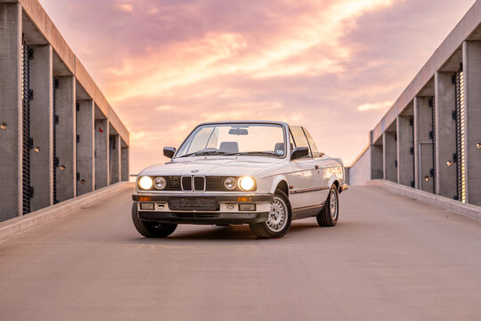 Riga, Latvia - May 26, 2025: A beautifully vintage BMW E30 Convertible is parked elegantly against a breathtaking and stunning sunset backdrop scenery