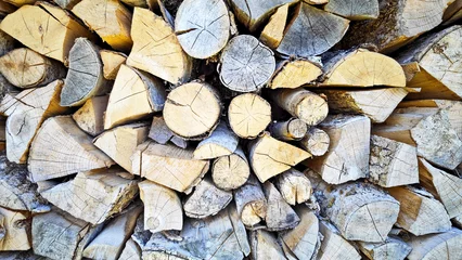 Gordijnen A full-frame close-up of a neat and rustic stack of chopped firewood logs. The image is a rich texture of different wood types, showcasing the variety of colors, grains, and cracks from the cut ends.  © IbrahimAlkan
