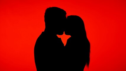 Silhouette of a Couple Kissing Against a Vibrant Red Background