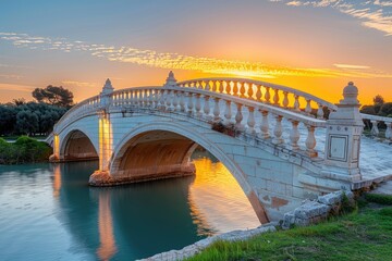Obraz premium Majestic stone bridge over tranquil water at sunrise.