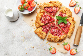 Delicious homemade strawberry galette with almond flakes being sliced on baking paper