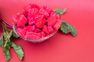 Diced beets in a glass bowl on a reddish-pink background
