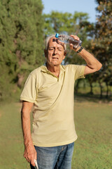 Senior man cooling down with water bottle on forehead during summer heat