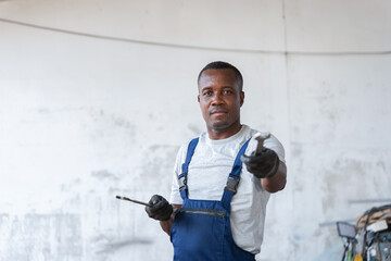 Mechanic with Wrench in Workshop, Smiling African American Tradesman Ready to Work, Professional Repairman Holding Tool Looking at Camera.