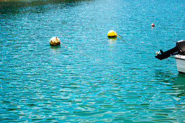 Bright blue ocean with floating yellow buoys gently tethered by ropes. A motorboat with its engine...