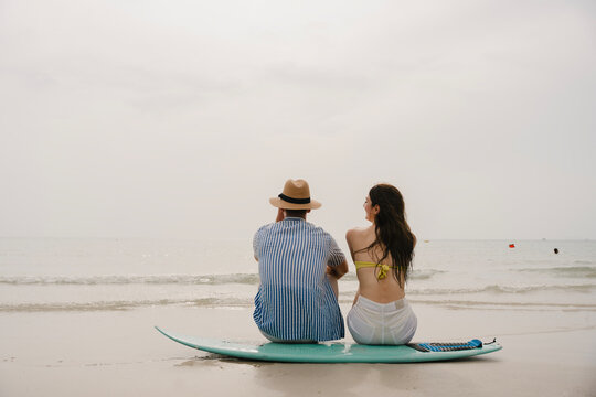 Happy young couple with surfboards enjoying a tropical beach holiday by the turquoise sea on a paradise island. capturing the lifestyle of happy people on a relaxing holiday by the ocean. baech.