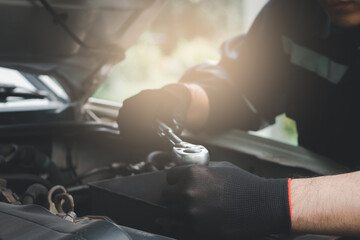 A mechanic is using a wrench to check a car engine.