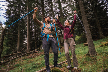 Young Hiking Couple Celebrating Success on Mountain Trail with Full Gear