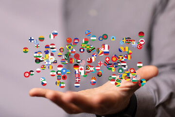 Diverse flags floating above a hand, symbolizing global connections and international collaboration.