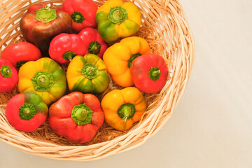 Orange and red ripe peppers. Sweet vegetables in a straw basket. Organic paprika. Top view. Place for text.